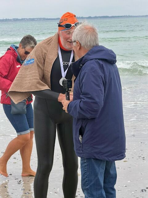 Swimmer being interviewed on the sand wearing his finisher's medal