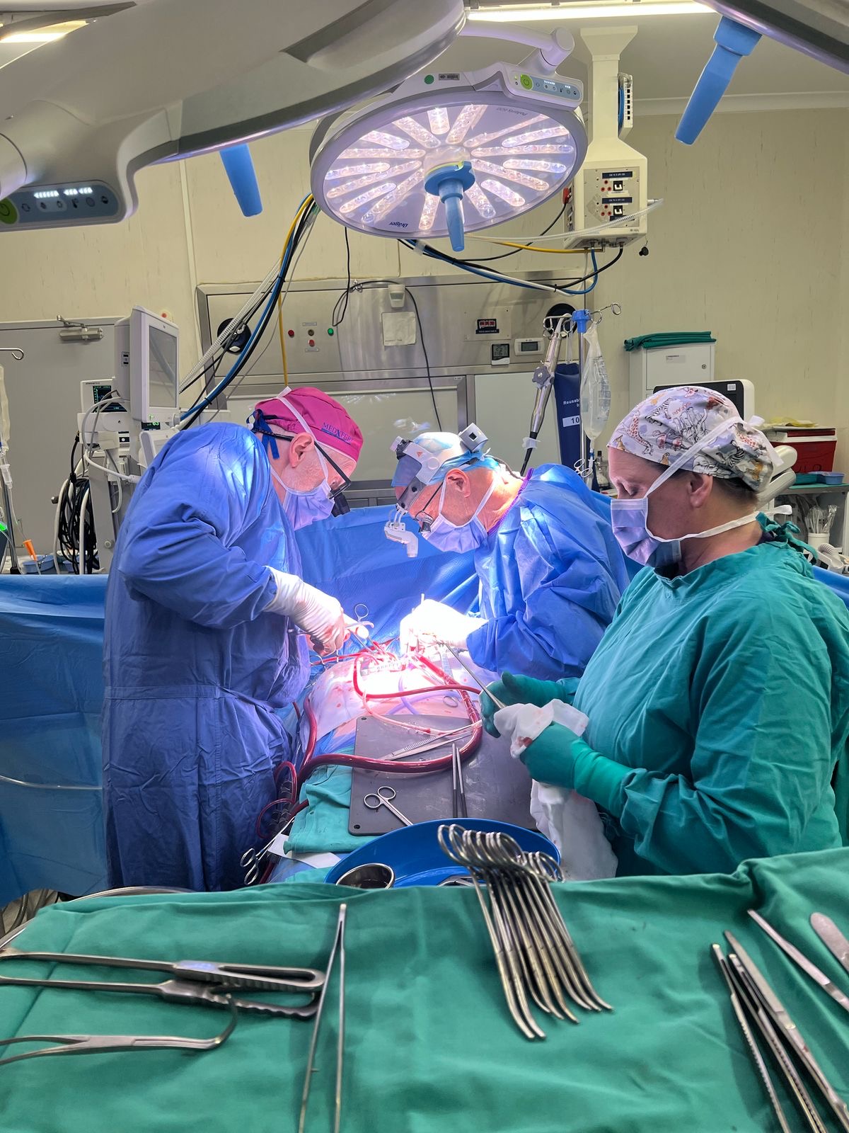 Surgical team operating under bright theatre lights during an open procedure