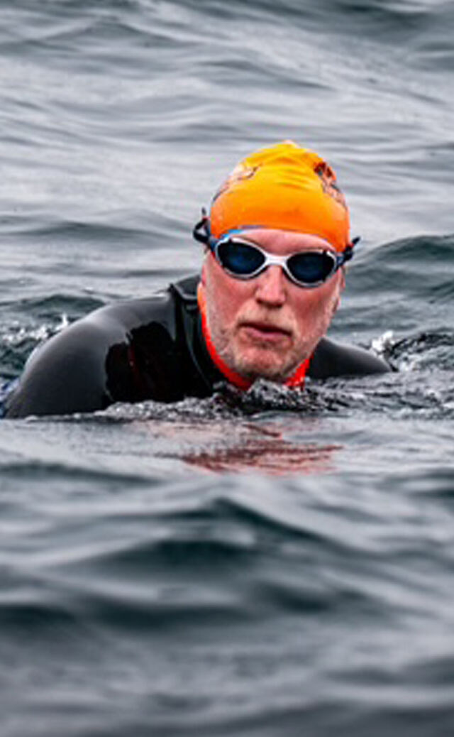 Close-up portrait of the swimmer in orange cap and goggles between strokes
