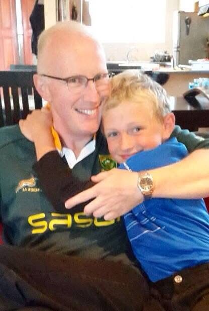 Young son hugging his father wearing a Springbok jersey