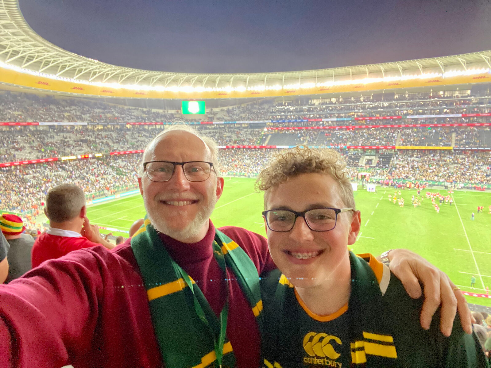 Father and teenage son at a rugby match in Cape Town Stadium at night