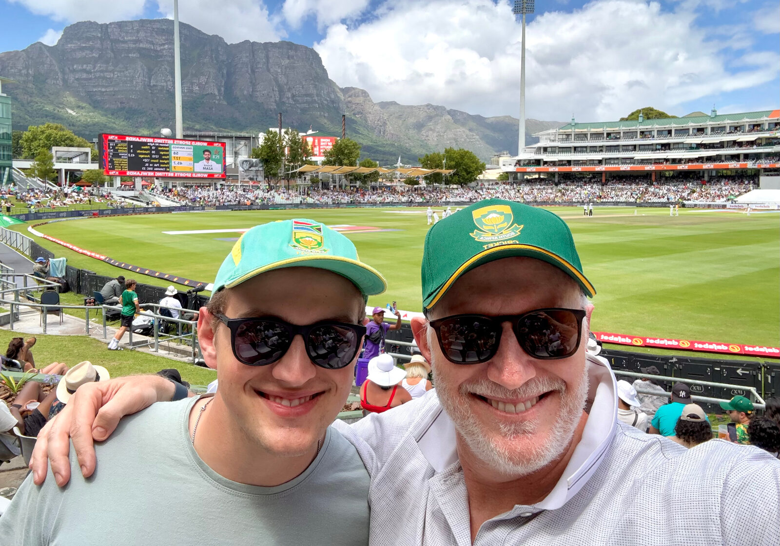 Father and adult son in Proteas caps at Newlands cricket ground with Table Mountain