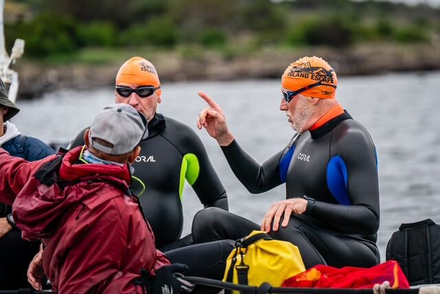 Swimmers and crew discussing the route from a small support boat