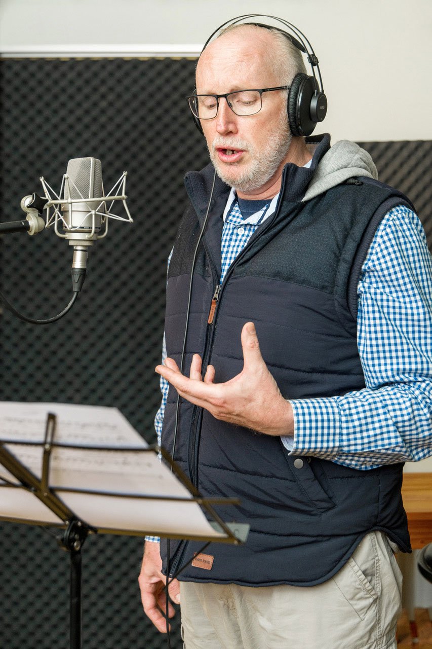 Dr Wilhelm Lichtenberg singing into a studio microphone while wearing headphones